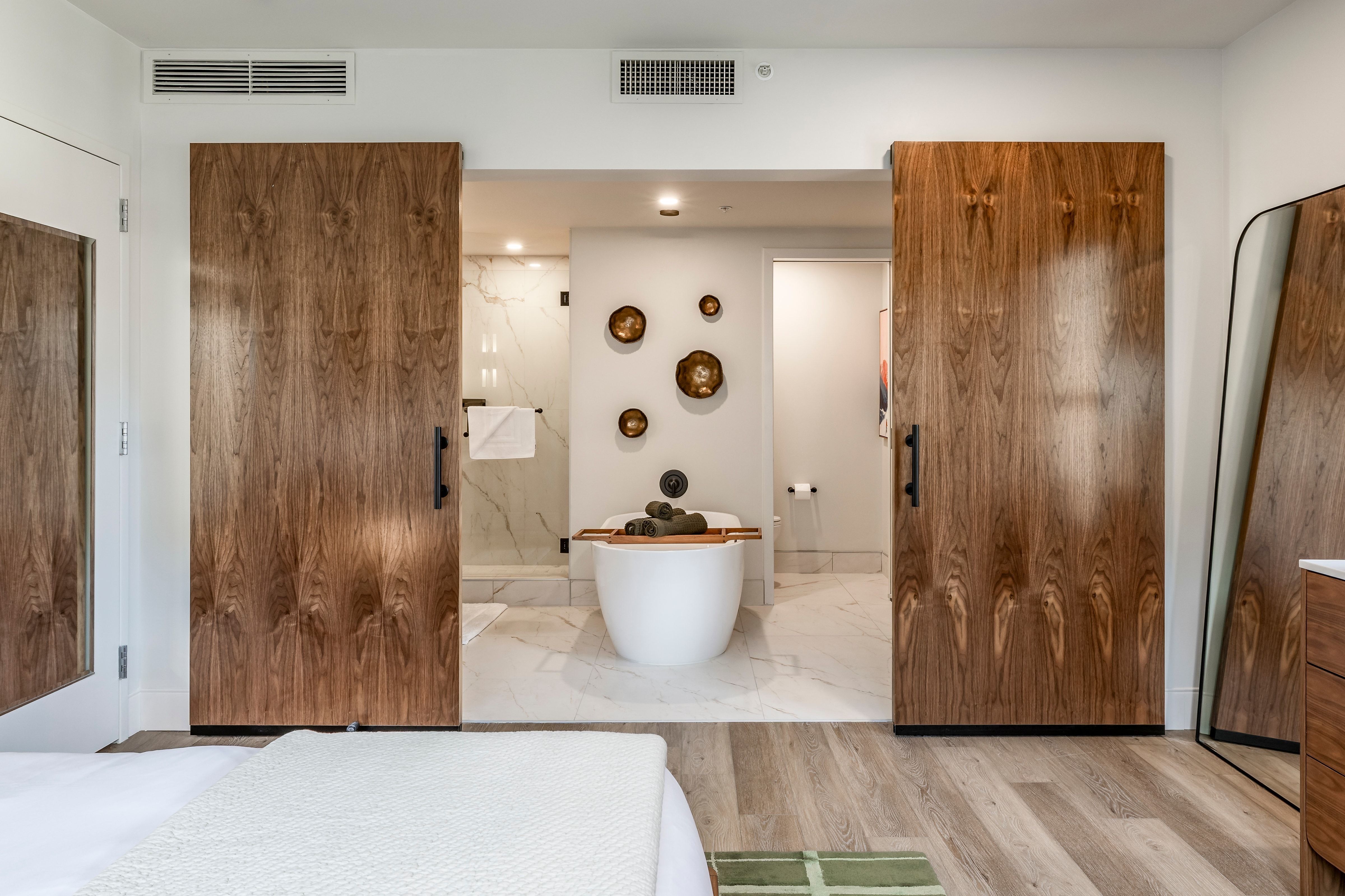 A hotel room with a large bed and a freestanding tub in the bathroom