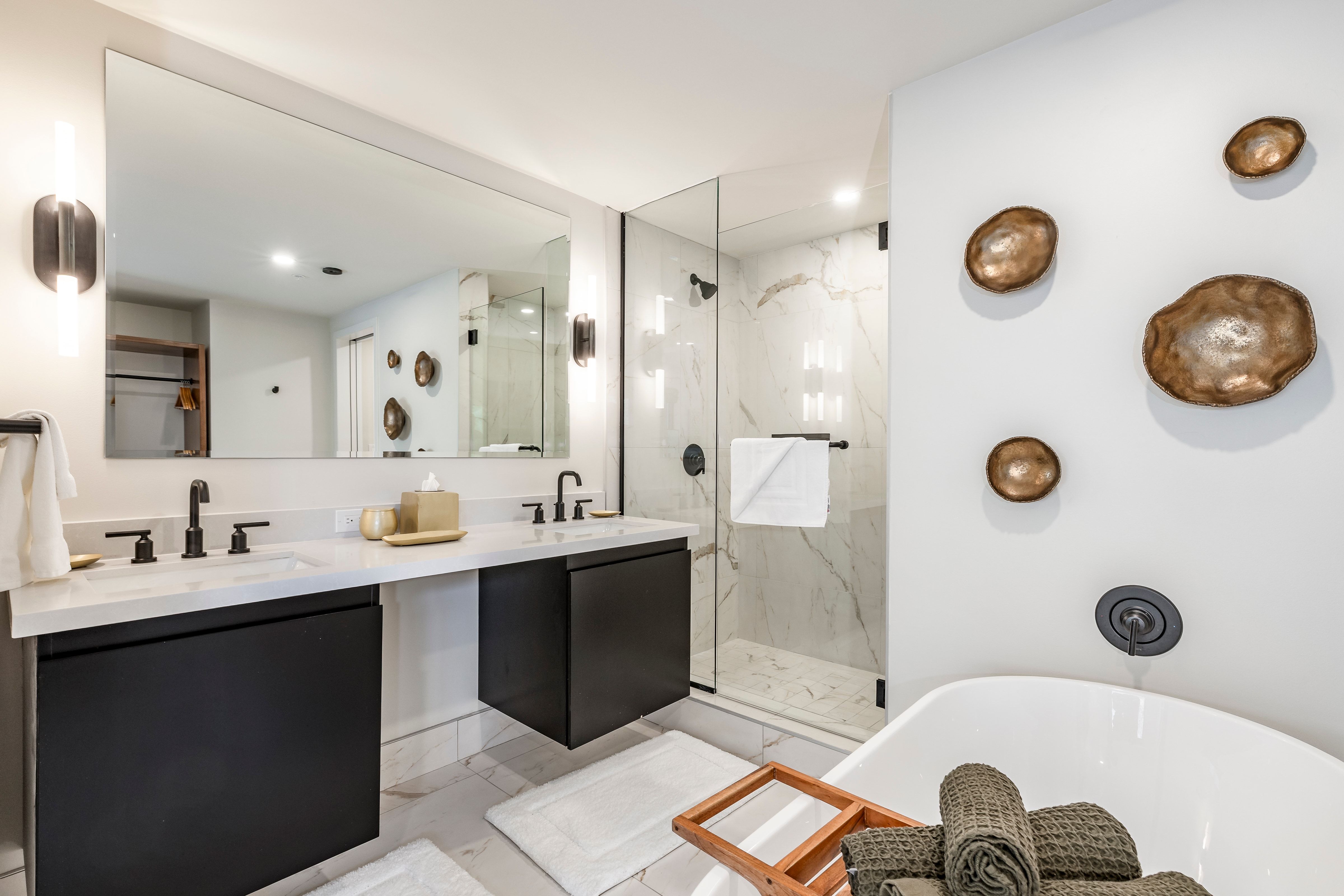 A modern bathroom with a double vanity, glass-enclosed shower, and a freestanding bathtub.