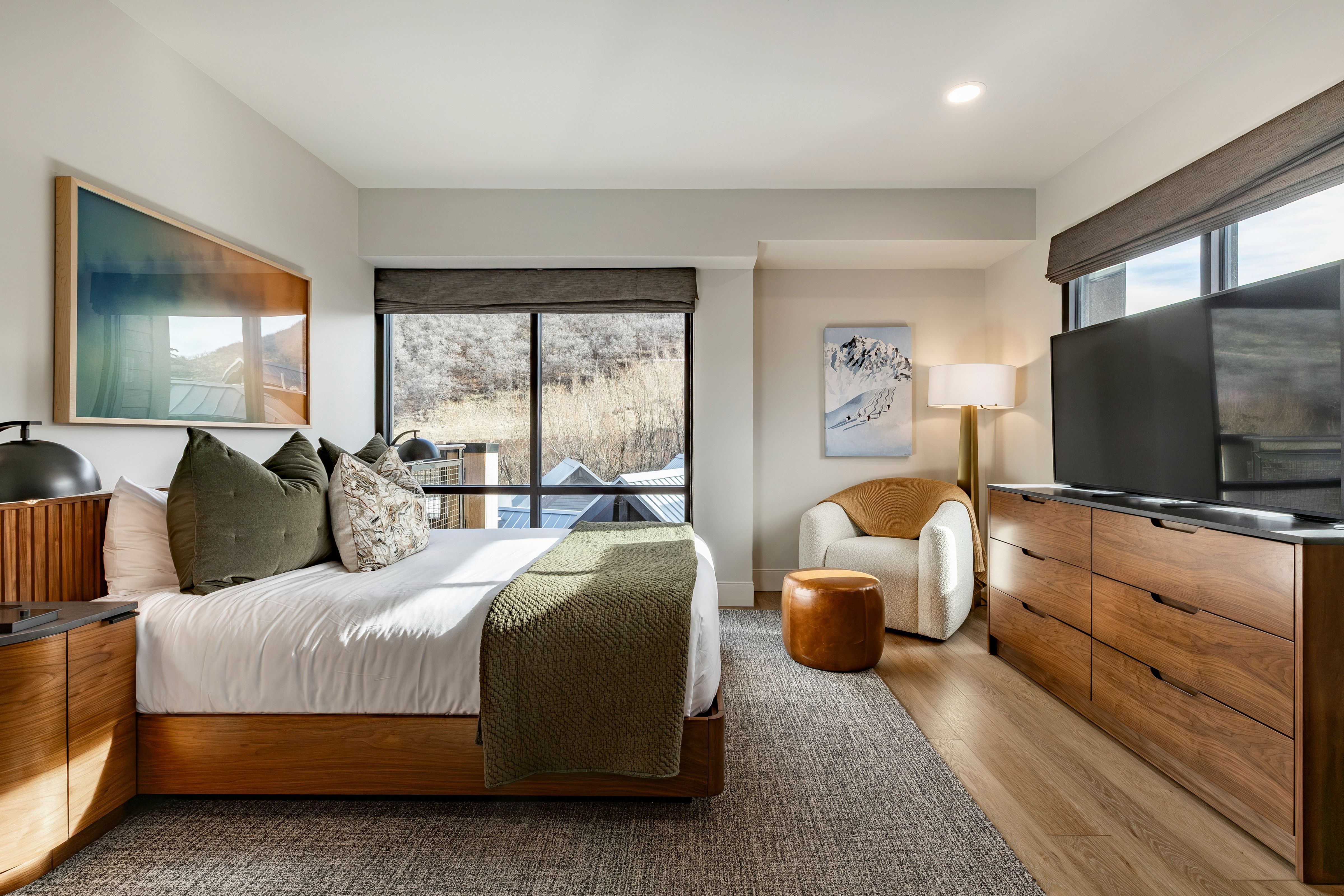 A hotel room with a bed, TV, chair, and window