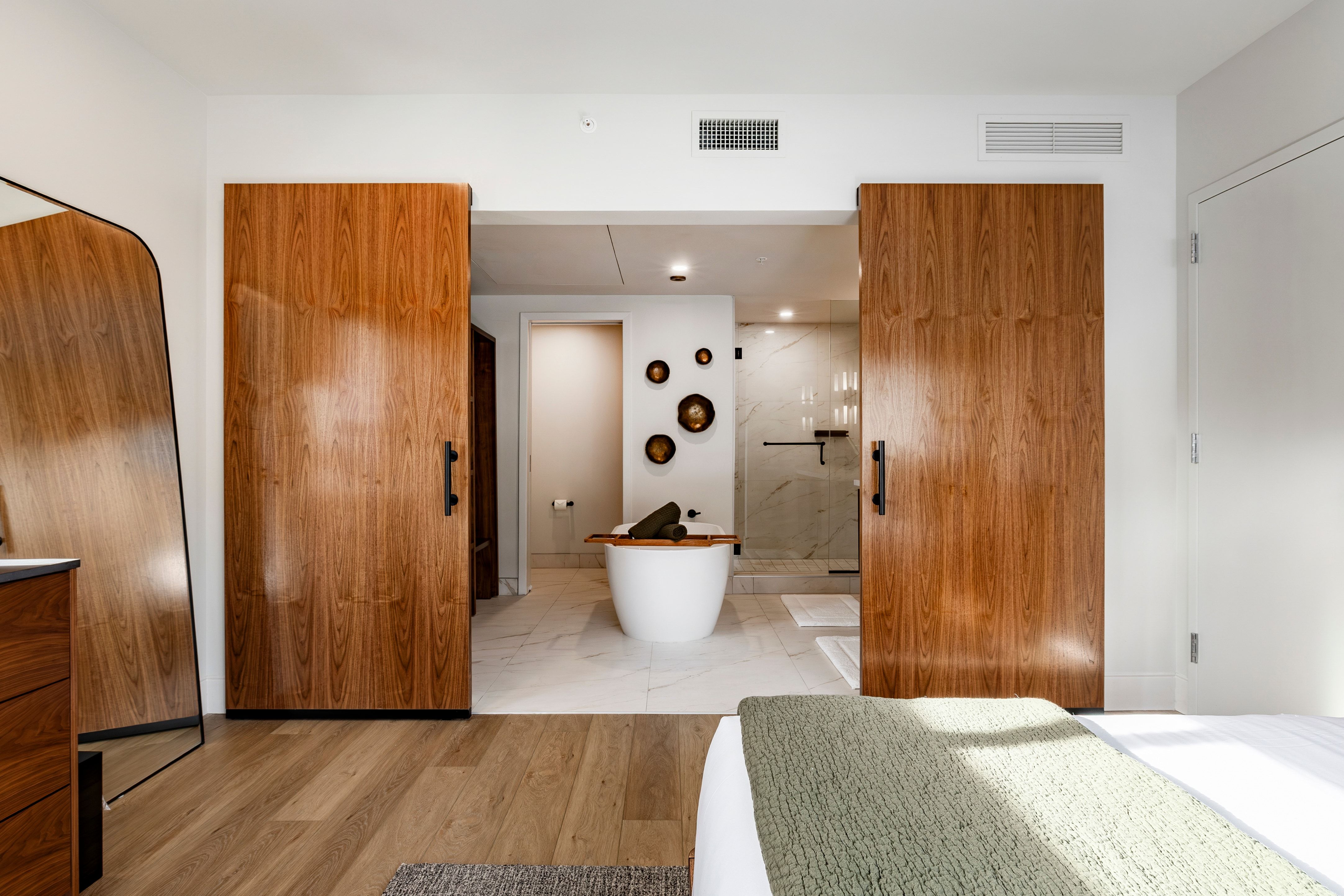 A hotel room with a large bed, wooden doors, and a bathtub in the bathroom