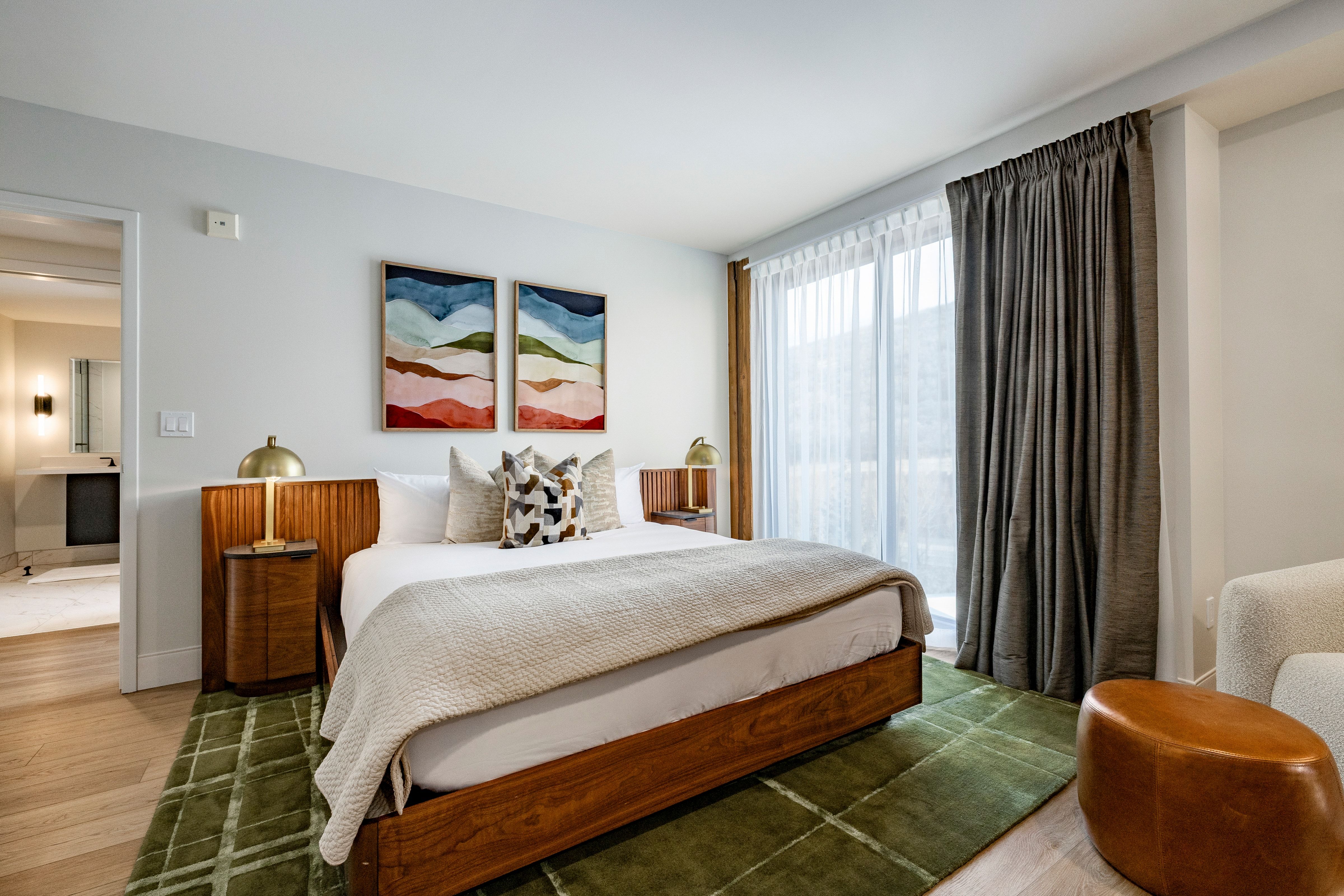 A wide view of a hotel room with a bed, nightstands, and artwork.
