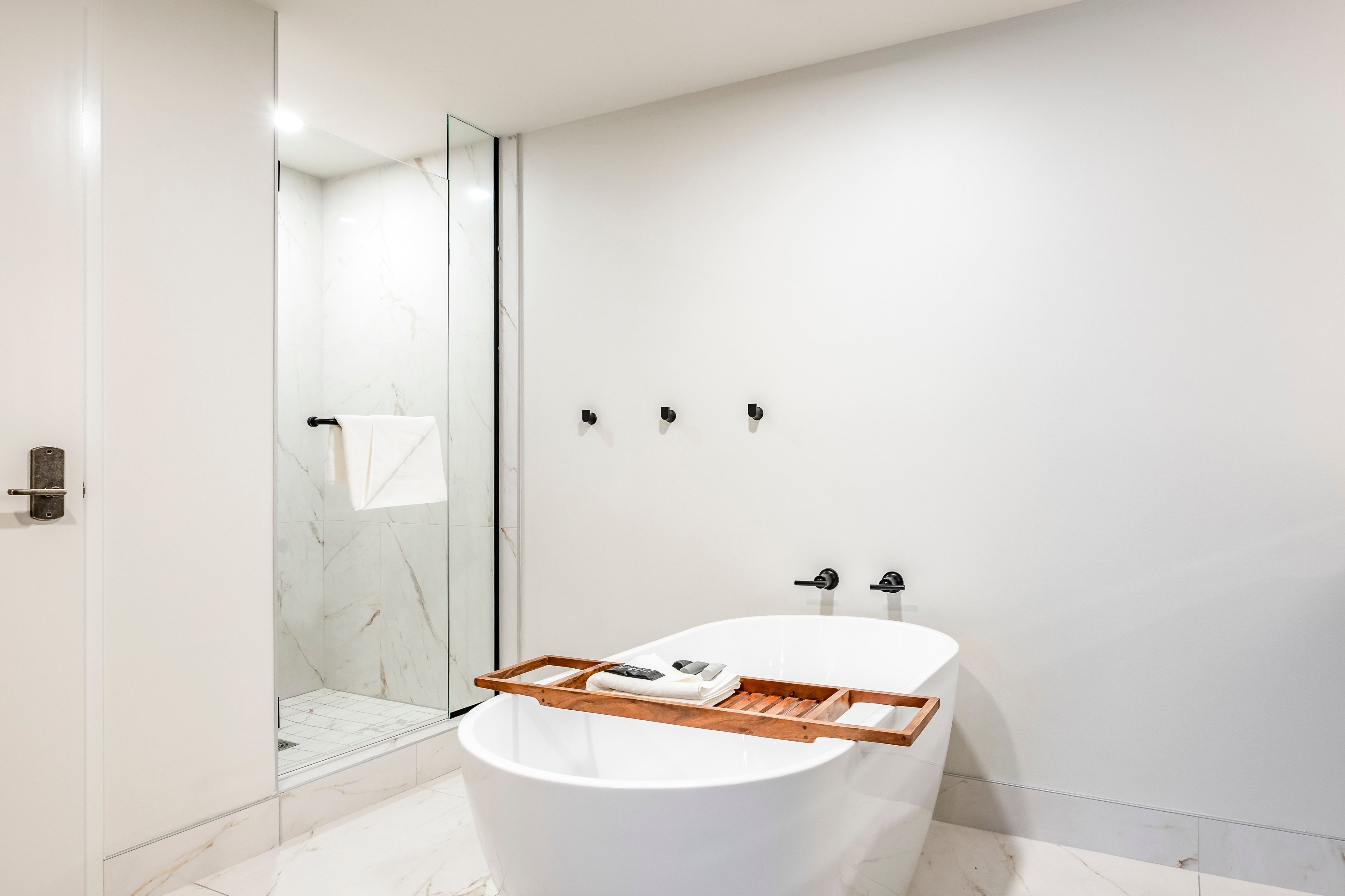 A modern bathroom with a freestanding bathtub, a glass-enclosed shower, and marble walls and floor.