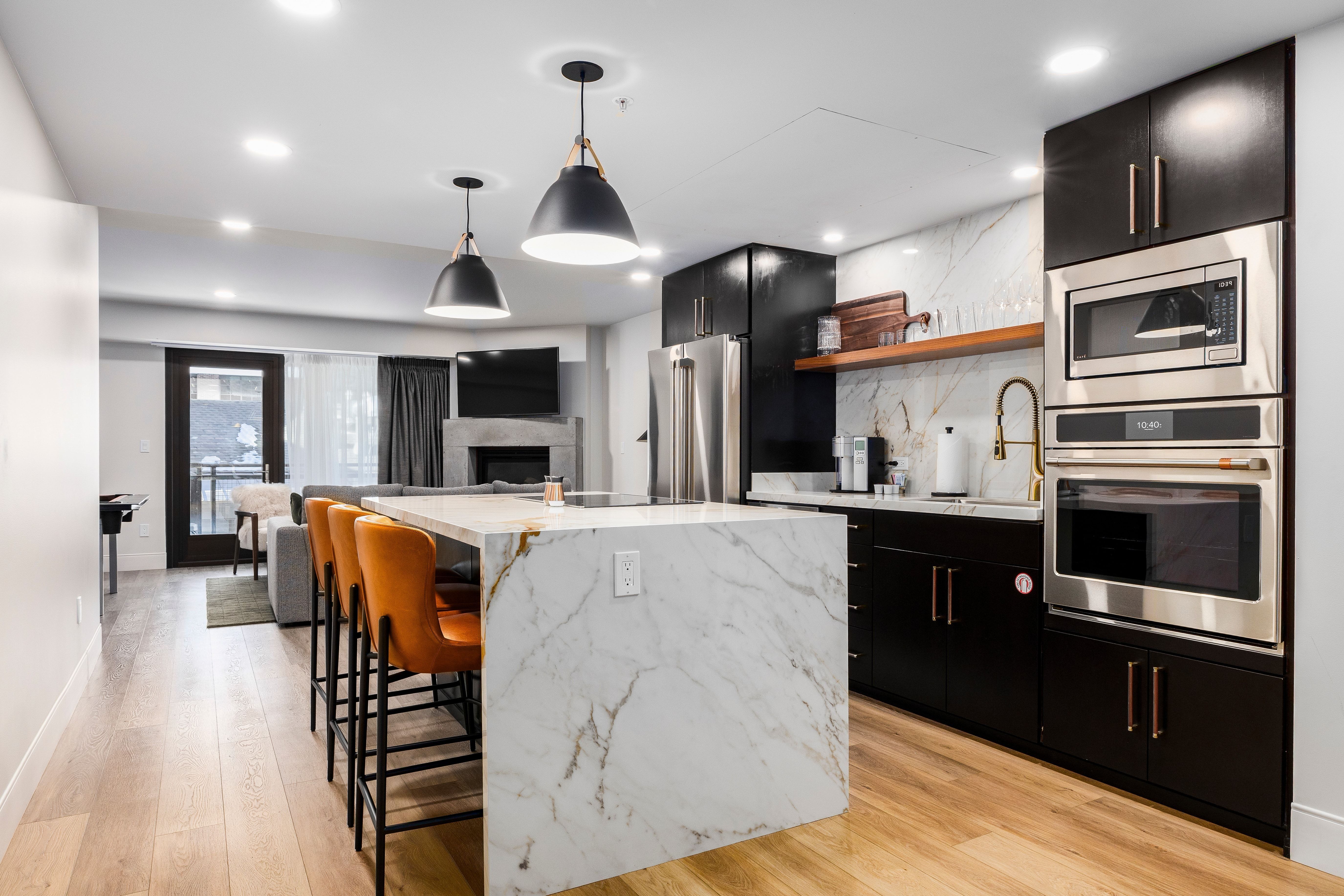 A modern kitchen with a large island, marble countertop, and stainless steel appliances.