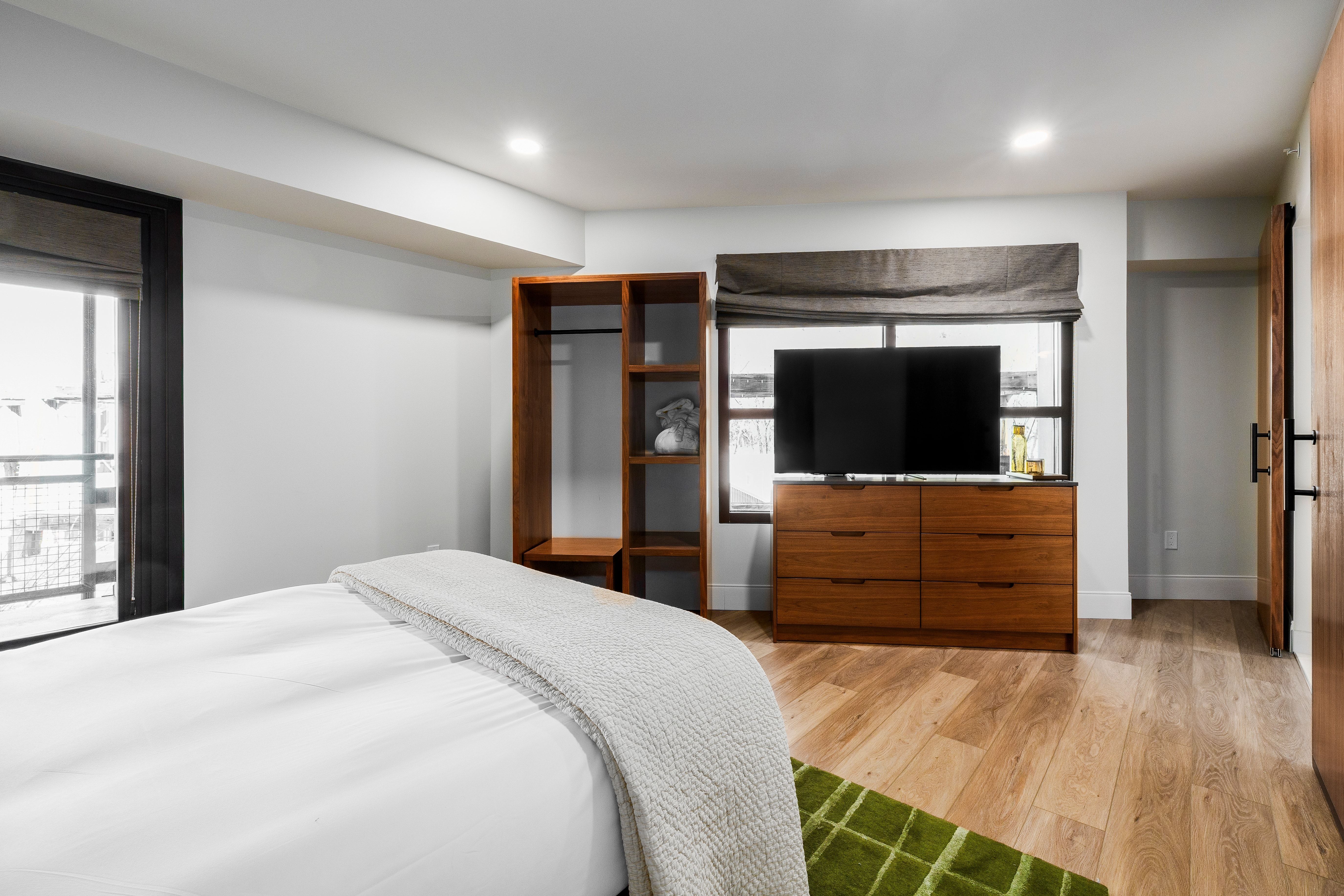 A hotel room with a bed, TV, and window