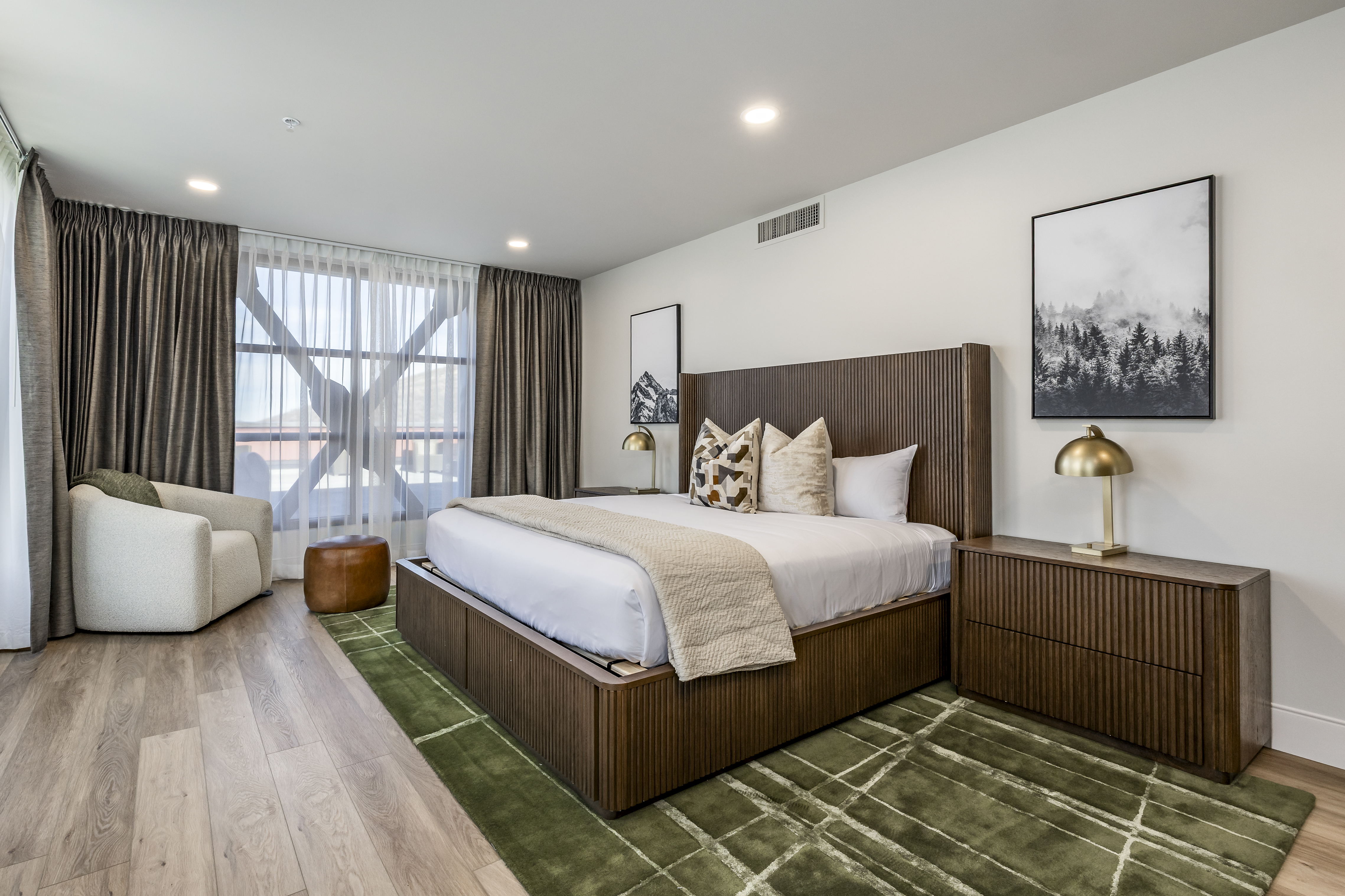 A wide view of a hotel room with a large bed, comfortable seating, and a window.