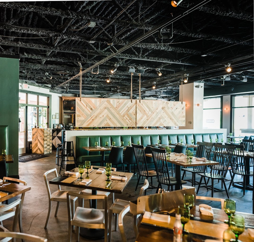 A dining area with tables, chairs, booths, and a bar.